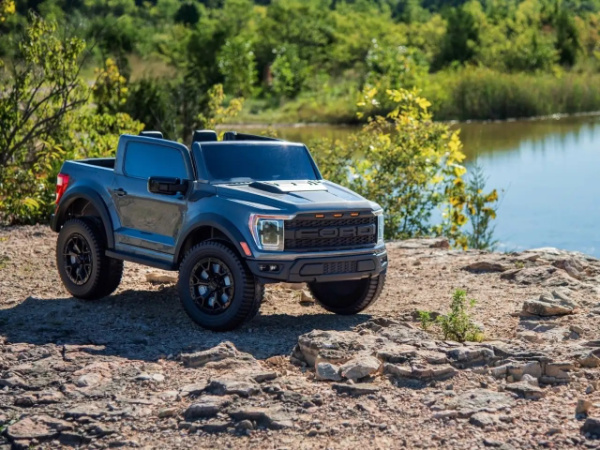 fordf150raptor ride on toy stock image on rocks with wooded backgound on lake on the right side of the image. 